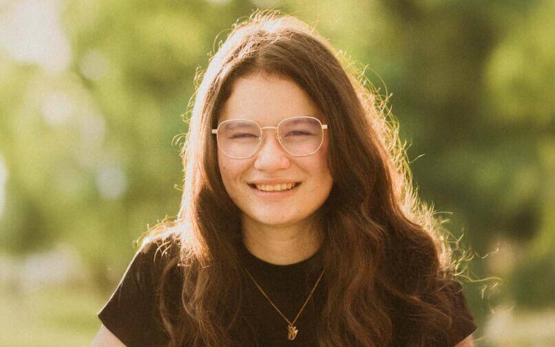 chica con gafas sonriendo a una cámara